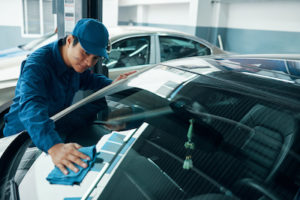 Auto glass mechanic cleaning windshield after glass repair